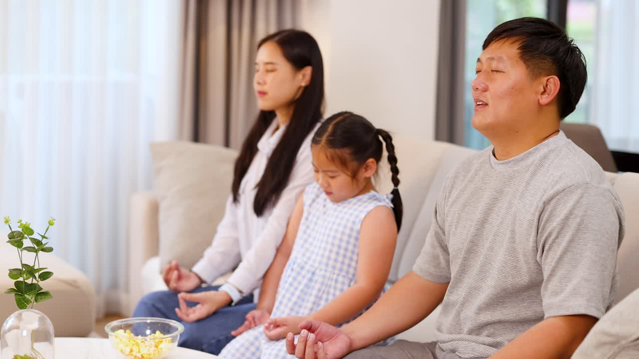 Three family members meditate peacefully in a bright living room with soft natural lighting