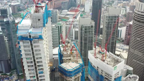 cinematic elevation shot capturing various high rises skyscrapers under construction, tilt up reveals downtown kuala lumpur cityscape with the tallest building merdeka 118 in the skyline