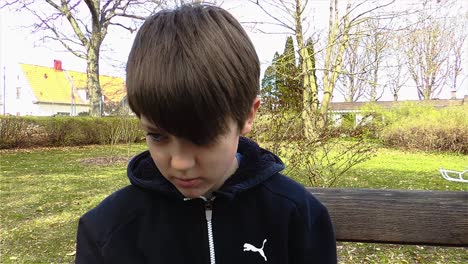 young boy eating lunch on park bench