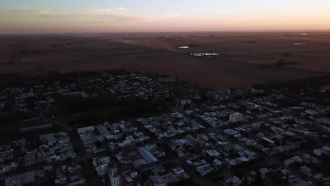 drone aerial panning view of a country city in the sunset with trucks dusty clouds in the horizon in the harvest time