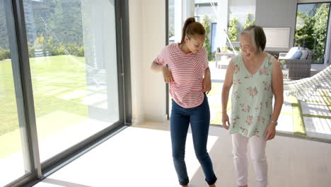 abuela asiática y nieta biracial bailando dentro de la casa