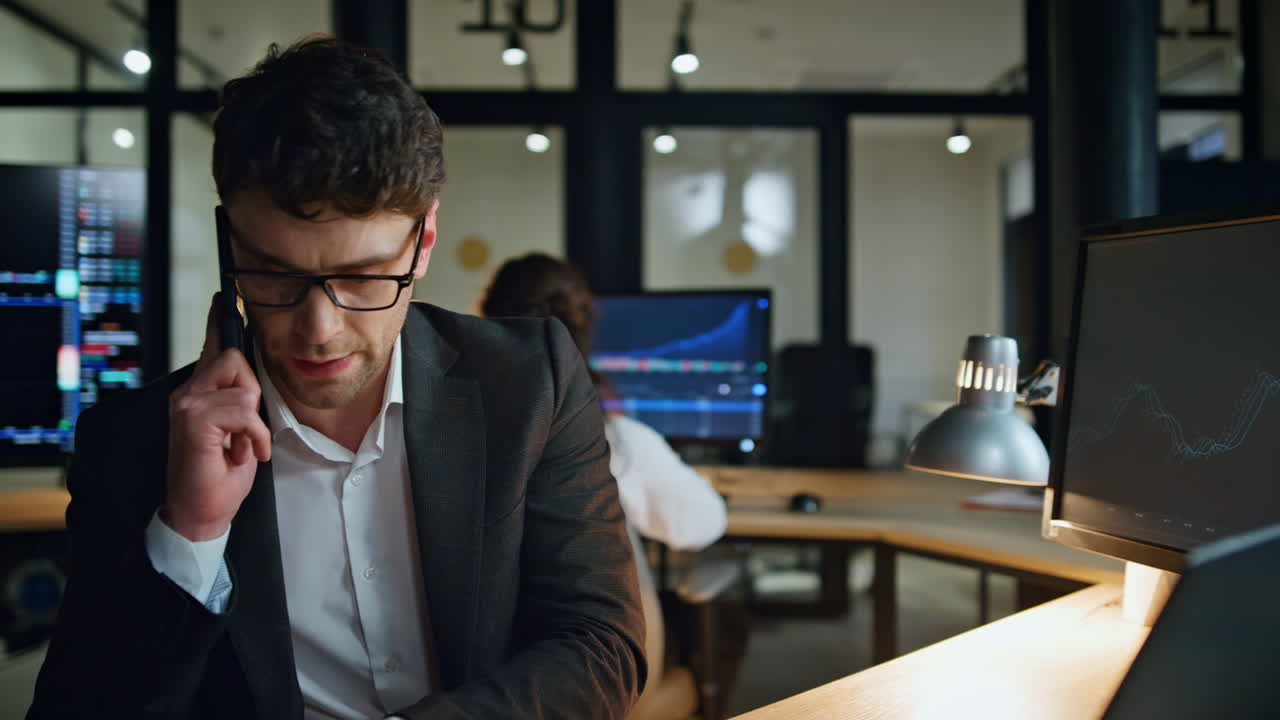 Responsabile di borsa che parla al cellulare in ufficio la sera. Un broker concentrato discute.