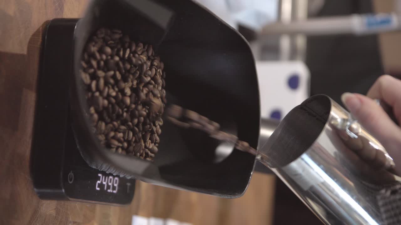 Vertical, hand carries small metal scoop pot, coffee beans fall into bowl to measure