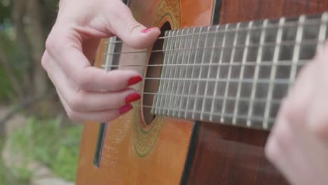 mujer con uñas pintadas de rojo toca una guitarra española
