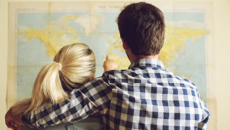 una joven pareja de turistas mirando el mapa del mundo