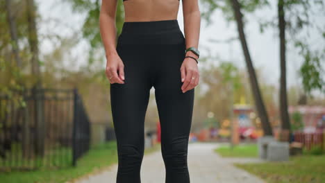 young athlete performing squat exercise outdoors in game park with blurred background showcasing trees and colorful game machines,focus on fitness and strength training