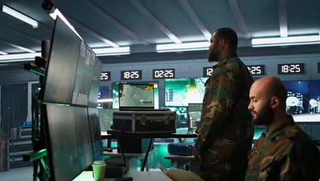 experto del ejército examinando datos en la sala de monitoreo con una computadora portátil