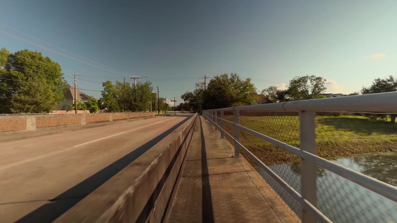 A POV shot of riding a bicycle over a narrow bridge in Houston, Texas.