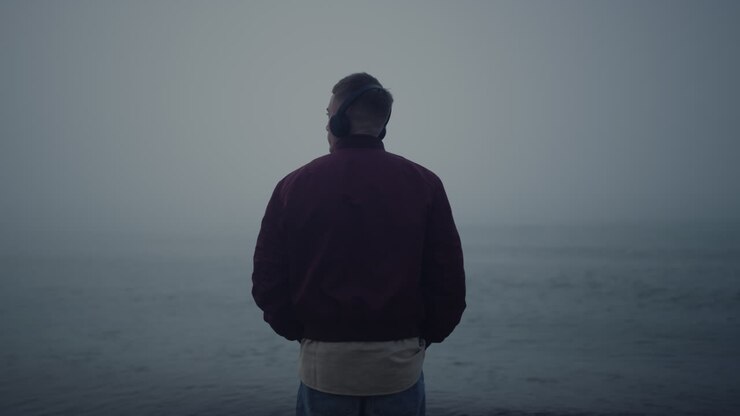 Man listening music headphones on sea beach. Guy enjoying music in earphones