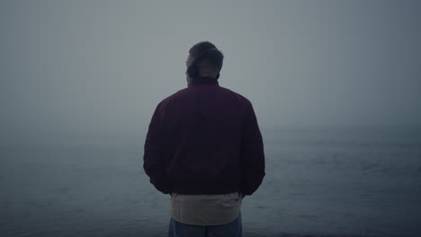 Man-listening-music-headphones-on-sea-beach.-Guy-enjoying-music-in-earphones