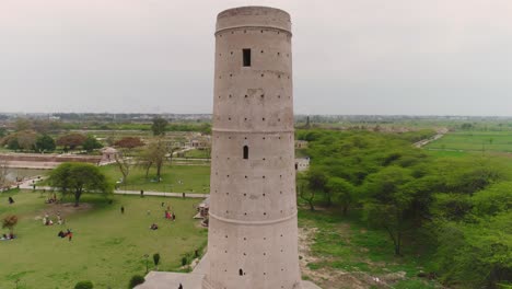 tracking aerial shot of hiran minar tower, tourists visit famous landmark in pakistan