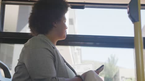 happy plus size biracial woman using smartphone in bus