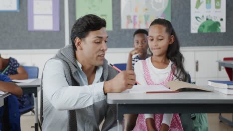 un maestro feliz y diverso que ayuda a los escolares a escribir en el aula de la escuela primaria