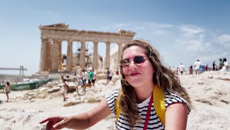 happy tourist waving for a selfie at the parthenon, athens, greece
