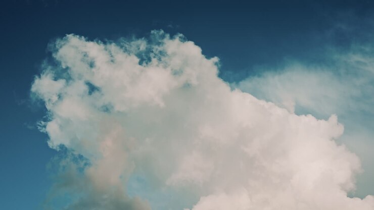 Close up of large, soft white clouds drifting across a blue sky