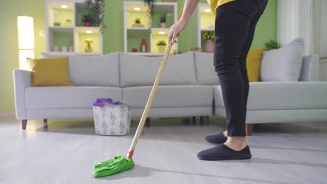 clumsy young man mopping the house slips and falls on the wet floor.