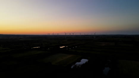 wind energy farm working on sunset in puck city, pomorskie zone, poland, drone pull out motion