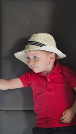 little boy traveler puts sunglasses on big black suitcase. toddler in hat rests in hotel after arrival in tropical country upper close view