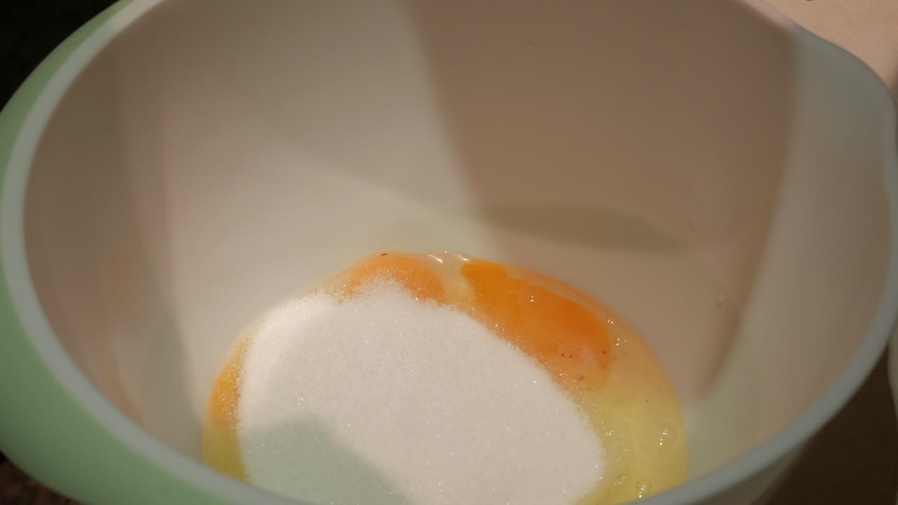 Mixing eggs and sugar in a bowl for baking, emphasizing preparation