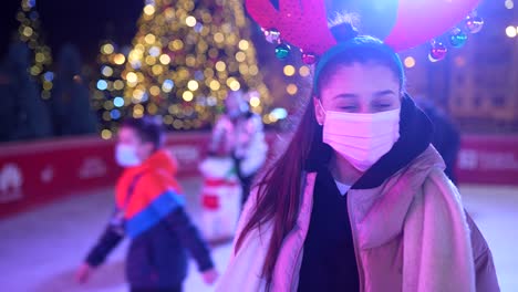 niña patinando en el hielo en la pista de patinaje de navidad