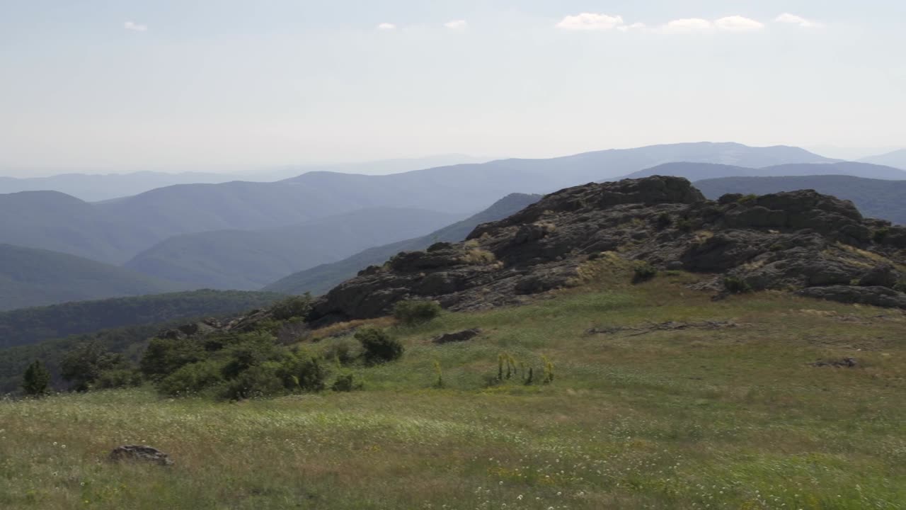 Panning shot of a stunning mountain landscape with rolling hills and valleys under a clear blue sky. Beauty of nature in peaceful outdoor setting. Stara Planina next to Sliven city. Balkan Mountains