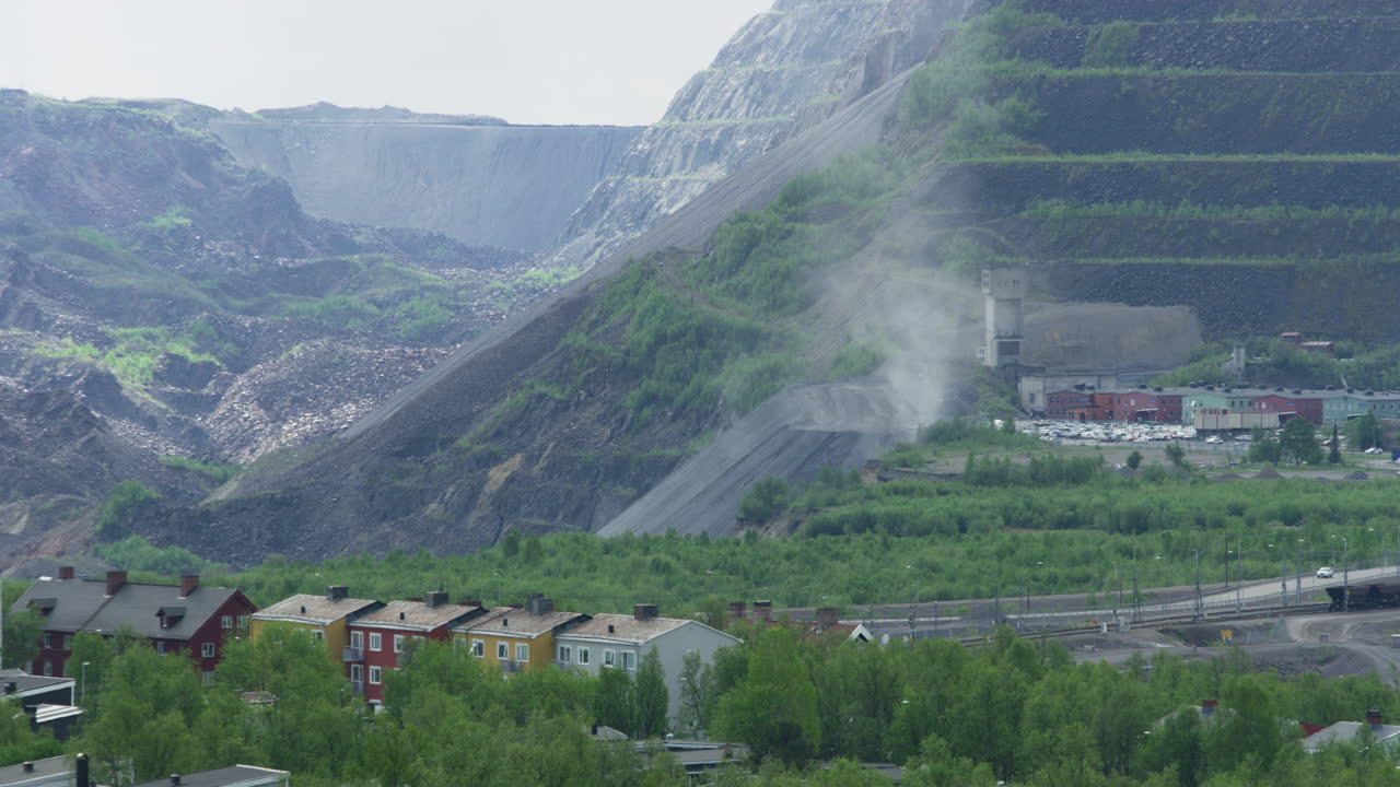 Close up shot of iron ore mine run by Luossavaara-Kiirunavaara AB LKAB in Kiruna, Norrbotten, Lapland, Sweden. Dust rising from the rocky talus slope at the bottom of the mine benches. Summer, day