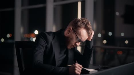 portrait of a stylish man sitting at a table with a notebook in a bad mood