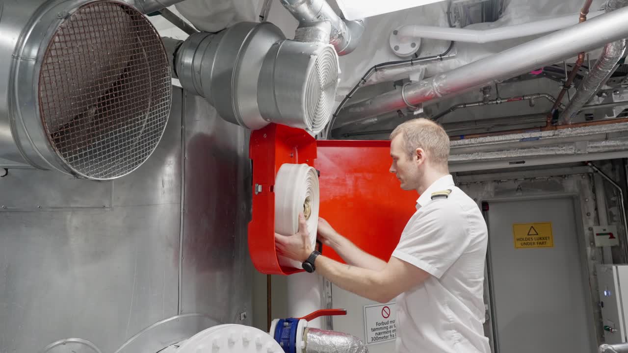 선장은 선박 엔진  지역의 소방 호스를 검사합니다.