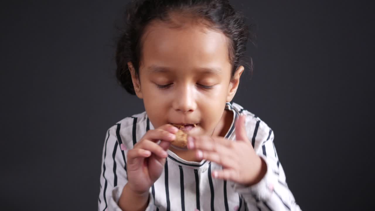 Bambina che mangia un biscotto