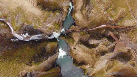 Río-De-Aguas-Bravas-Que-Fluye-En-El-Cañón-Fjadrargljufur,-Acantilados-De-Hierba-Erosionados