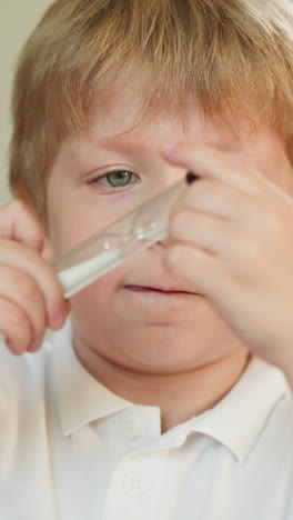 curious little blond boy looks at hourglass in children room closeup. thoughtful preschooler child learns sand-glass in kindergarten class at lesson