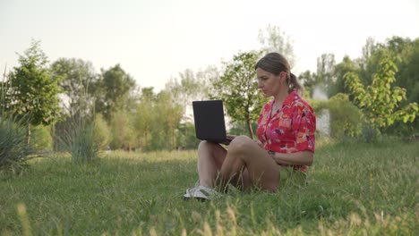 a middle-aged woman works using her laptop in a public park. she types and thinks.