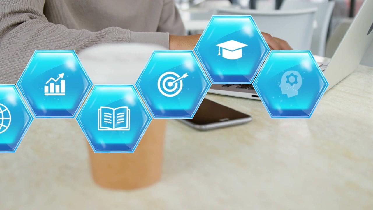 Man reaching for coffee cup then typing on laptop, sending education hex icons sliding across table