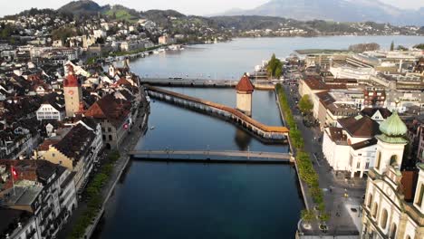 Vista-Aérea-De-Lucerna,-Suiza-Desde-Lo-Alto-Mientras-Se-Mueve-Desde-La-Iglesia-Jesuita-Sobre-El-Puente-Kappelbrücke-Hacia-El-Lago