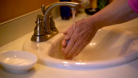 slow motion of caucasian woman washing hands getting them wet and scrubbing in a home bathroom