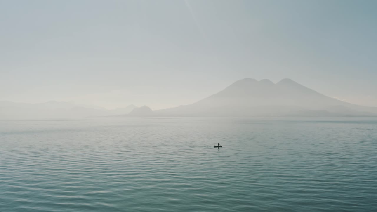 과테말라 아티틀란 호수에서 아침 동안 보트에 탄 남자를 향해 드론 공중 비행