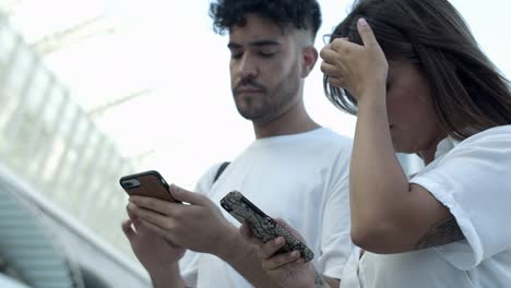Low-angle-view-of-young-people-using-smartphones-on-street