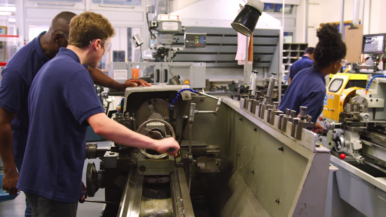 ingeniero mostrando a un aprendiz adolescente cómo usar un torno