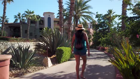 Back-of-Lonely-Female-Walking-on-Trail-in-Tropical-Garden-of-Luxury-Hotel,-Static-Shot