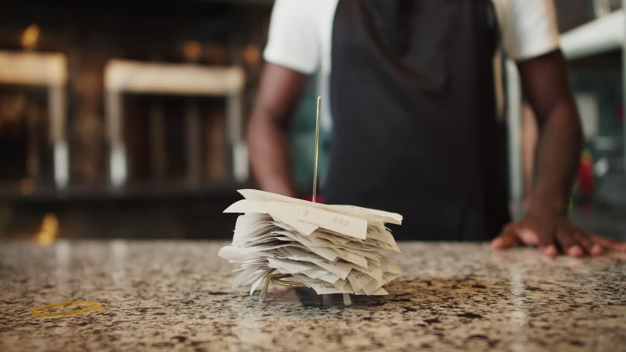 Close-up shot: a man puts a check with the rest of the checks on a special metal rod for checks. Facility tracking
