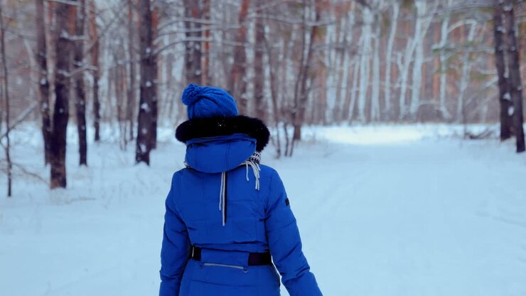 Pretty young woman walks through a forest in winter. Woman looks around and takes a walk on a winter day. Circular span of the camera.