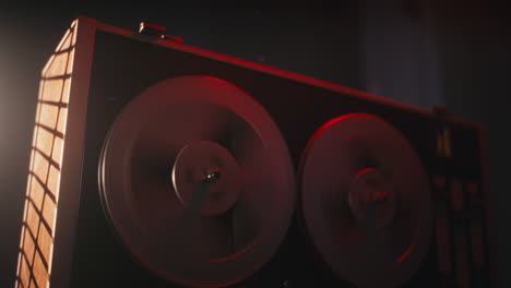 a vintage tape recorder spinning spools in a red blinking light