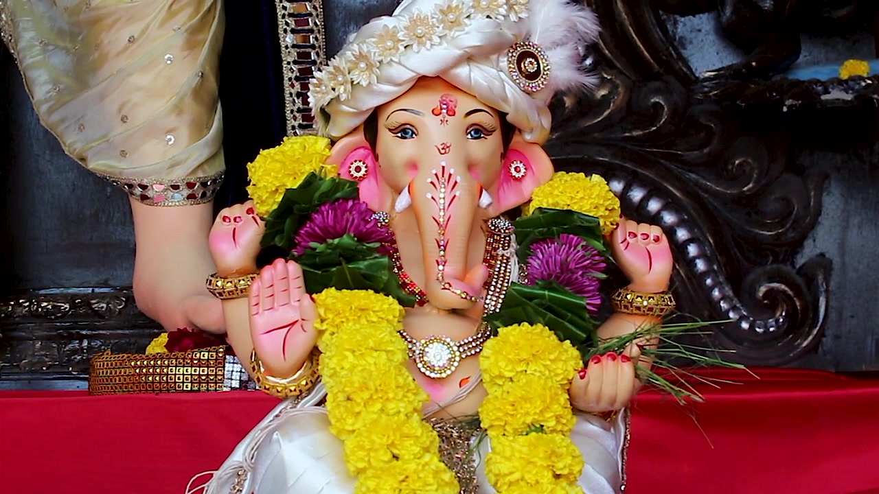 Idolo di Mangal Murti Ganesha decorato con fiori di calendula, turbante ornato e gioielli durante il festival di Ganesh Chaturthi in India, primo piano della tradizionale celebrazione religiosa indù