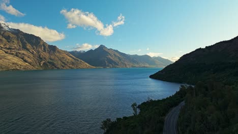 Dolly-Aéreo-A-Lo-Largo-Del-Lado-Sombreado-Del-Lago-Wakatipu-Con-Montañas-Iluminadas