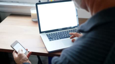 man using laptop and mobile phone in living room 4k