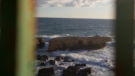 fotografía estática de las olas chocando contra una gran roca durante la hora dorada en siracusa, sicilia (sicilia, italia)