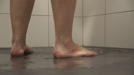 caucasian man takes shower at home, close up of feet and floor