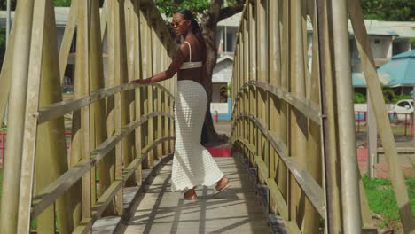 chica de piel oscura caminando por un puente en un vestido de playa sexy en una playa de una isla del caribe