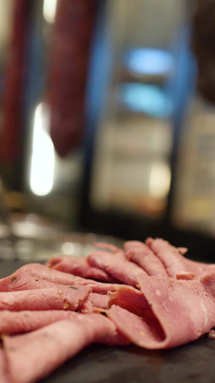 A static close-up shot of thinly sliced roast beef arranged on a dark platter