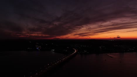 Eine-Brücke,-über-Der-Die-Sonne-Untergeht-Und-Einen-Panoramablick-Auf-Das-Meer